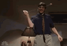 a man is dancing in a living room in front of a lamp and a football .