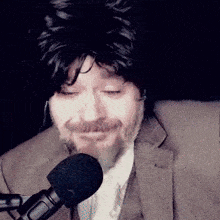 a man with a beard and a wig is speaking into a microphone