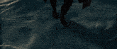 a man in a cape is running in the water near a ship