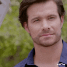 a close up of a man 's face with a beard and a blue shirt .