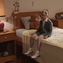a man sits on a bed with a teddy bear on it
