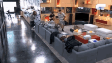 a group of people are standing in a living room with a couch