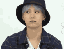 a young man wearing a hat and a plaid shirt is making a face .