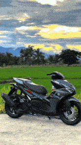 a black yamaha scooter is parked in front of a field