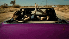two women in a purple car giving a high five
