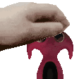 a hand is holding a red object that looks like a spider .