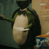 a turtle holding a piece of paper in front of a hbo sign