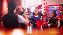 a man is taking a picture of a group of people in a room with hearts hanging from the ceiling