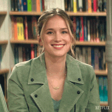 a woman wearing a green jacket is smiling in a library .