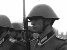 a black and white photo of a soldier holding a stick