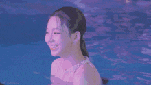 a woman with green hair is swimming in a pool and smiling .