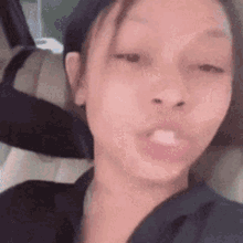 a woman is sitting in the back seat of a car with her mouth open and making a funny face .
