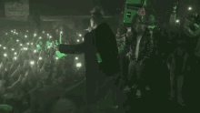 a man singing into a microphone in front of a crowd with a sign that says light on the wall behind him