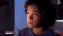 a young boy with curly hair is sitting in front of a computer monitor .