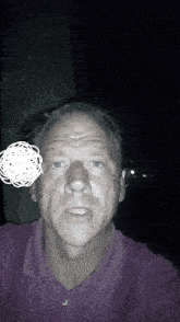 a man in a purple shirt takes a selfie