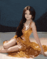 a woman in a long gold dress is sitting on the floor
