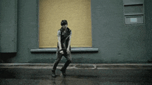 a man is walking down a street in front of a yellow roller shutter