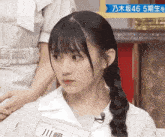 a girl with braided hair and a name tag that says ' 川 ' on it