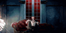 a man is sitting on a couch in front of a window