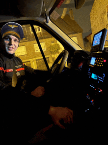 a man wearing a hat that says ' sdf ' on it is sitting in the driver 's seat of a car
