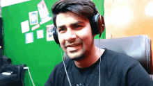 a man wearing headphones is sitting in front of a green screen