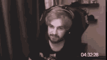 a man with a beard is wearing headphones and sitting in front of a computer screen .