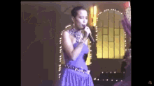 a woman in a purple dress singing into a microphone .