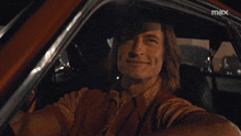 a man is taking a selfie in a car with a max logo in the corner