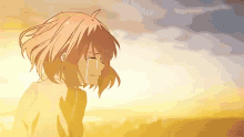a girl is crying with tears running down her face while standing in front of a sunset .