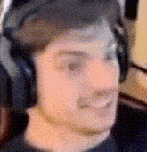 a blurry picture of a man wearing headphones and smiling .