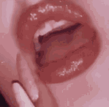 a close up of a woman 's lips with her tongue sticking out and white nails .