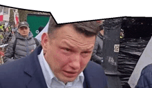 a man in a suit is crying in front of a crowd of people .