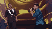 two men singing on a stage with the letters rtve on the bottom right