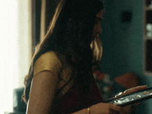 a woman in a yellow top is holding a tablet in her hand