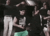 a man in a black shirt is dancing in a crowd .