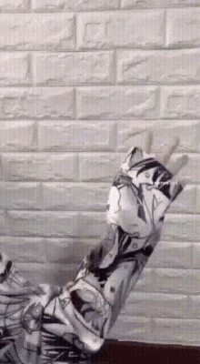 a person is standing in front of a white brick wall wearing a floral shirt .
