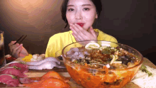 a woman in a yellow shirt is eating a bowl of food