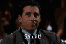 a man in a suit and tie is holding a drink and says sahhit