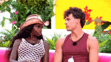 a man and a woman are sitting on a pink couch