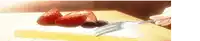 a person is holding a fork over a plate of strawberries and plums .