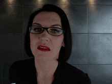 a woman wearing glasses and red lipstick is making a face
