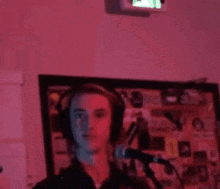 a young man wearing headphones is singing into a microphone in a dark room .