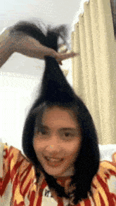 a woman is holding a bunch of hair in her hand and smiling .