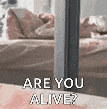 a person standing in front of a bed with the words `` are you alive '' written on it .