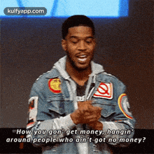 a man in a denim jacket is talking into a microphone and says how you gon ' get money
