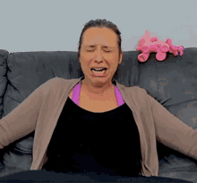 a woman is sitting on a couch with her eyes closed and a pink stuffed animal behind her