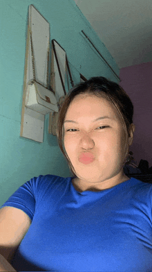 a woman in a blue shirt is taking a selfie