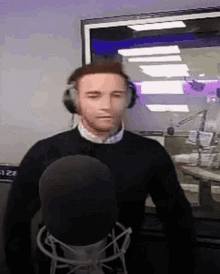 a man is wearing headphones and standing in front of a microphone .