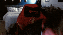 a red secret lab chair sits in a bedroom next to a bed