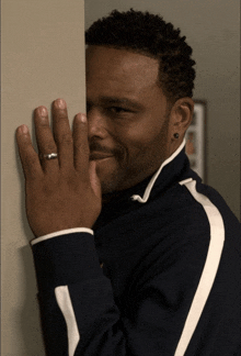 a man with a ring on his finger is peeking behind a wall